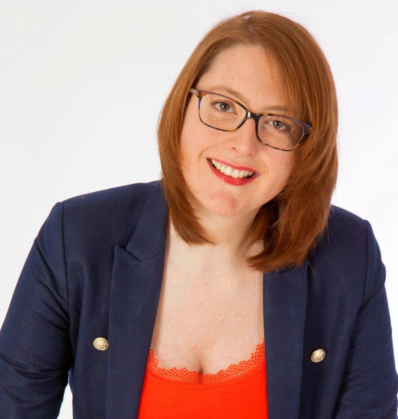 Portrait de Nathalie Chiffoleau, souriante, lunettes, veste bleu marine et haut orange